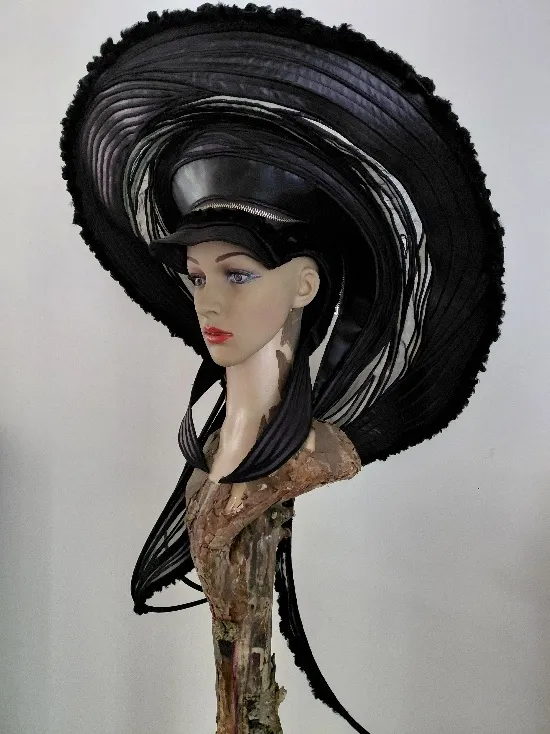 Zwart hoedobject met een grote spiraalvormige rand op een houten sculptuur